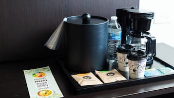 Un plateau contenant une machine à café, des bouteilles d’eau, des tasses à café et un menu.