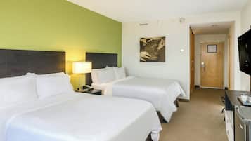 A hotel room with two beds, a desk, a TV, and a painting on the wall.