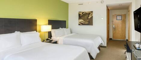 A hotel room with two beds, a desk, a TV, and a painting on the wall.