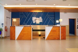 A reception area with a blue geometric wall design, a Holiday Inn Express sign, and two wooden reception desks. - Holiday Inn Express Managua by IHG (Managua)