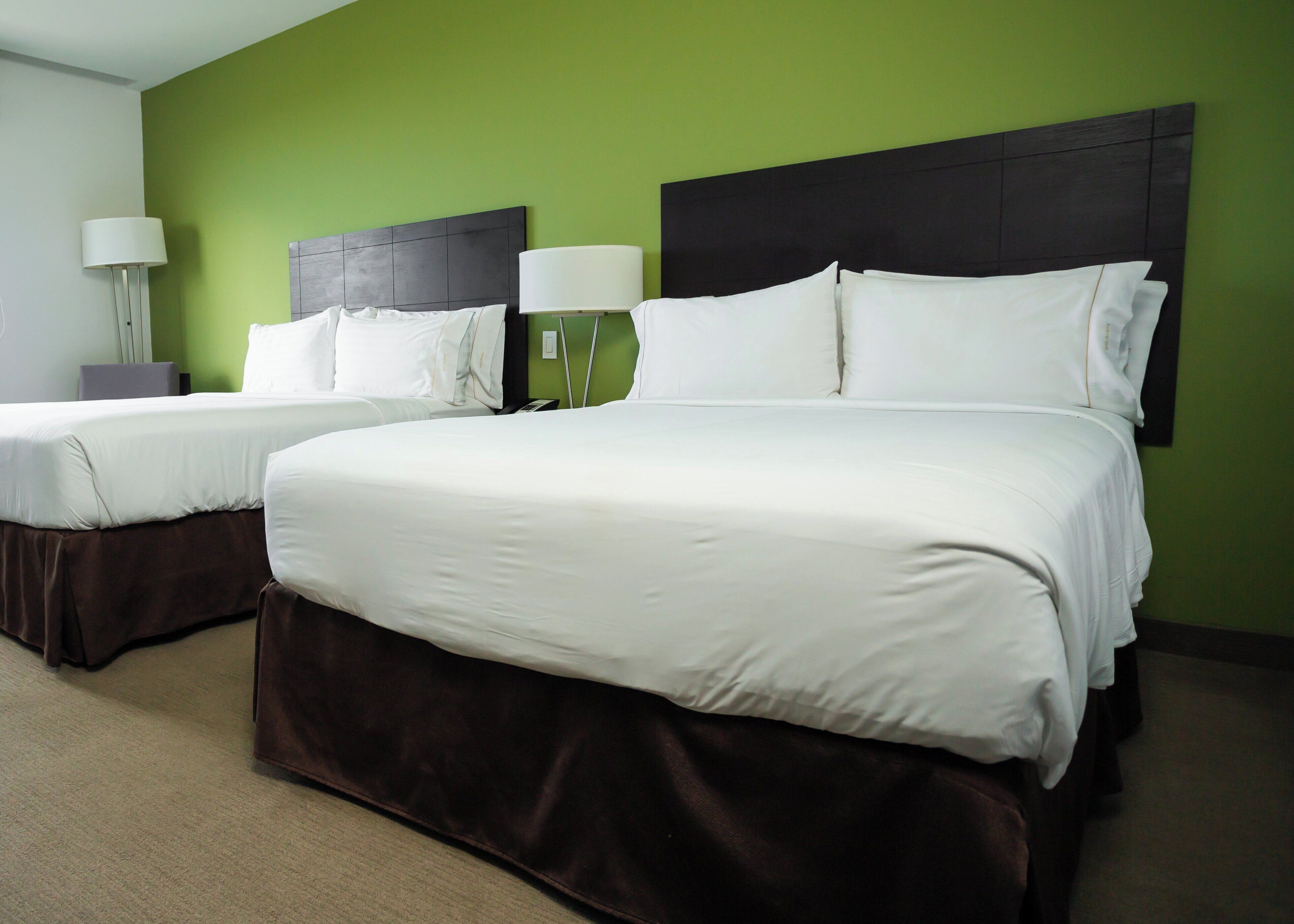 Ein Hotelzimmer mit zwei Betten, einer grünen Wand und einem dunklen Kopfteil.