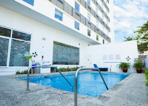 A modern building with a swimming pool, large windows, and potted plants. - Holiday Inn Express Managua by IHG (Managua)