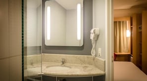 Une salle de bain avec un lavabo en marbre, un sèche-cheveux et un miroir avec éclairage intégré.