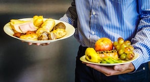 Une personne tenant deux assiettes, l’une contenant divers aliments et l’autre des fruits et une banane.