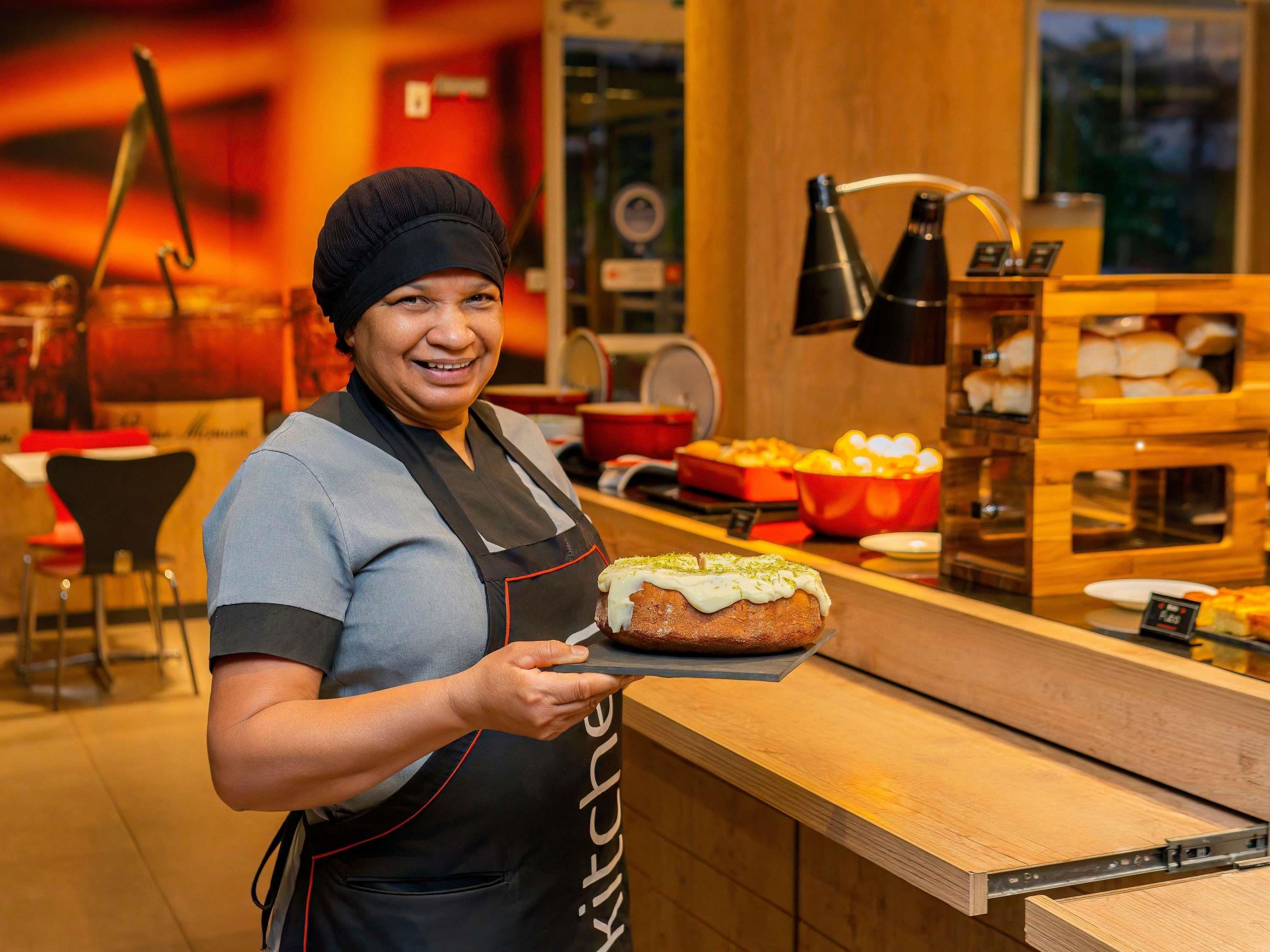 A person holding a tray with a pastry in a kitchen setting.