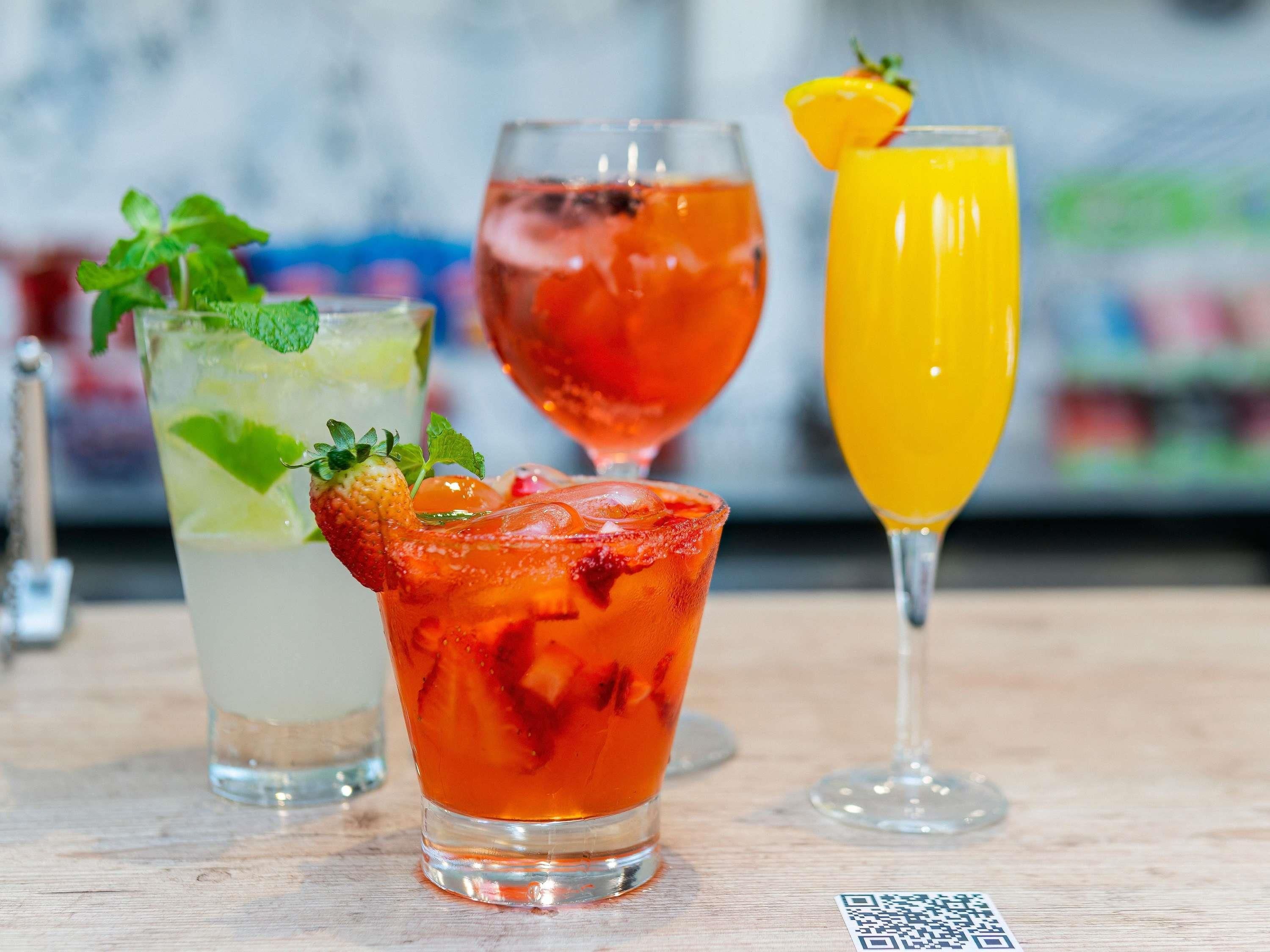 A variety of drinks in different glasses on a wooden surface.