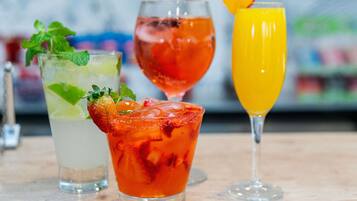 A variety of drinks in different glasses on a wooden surface.