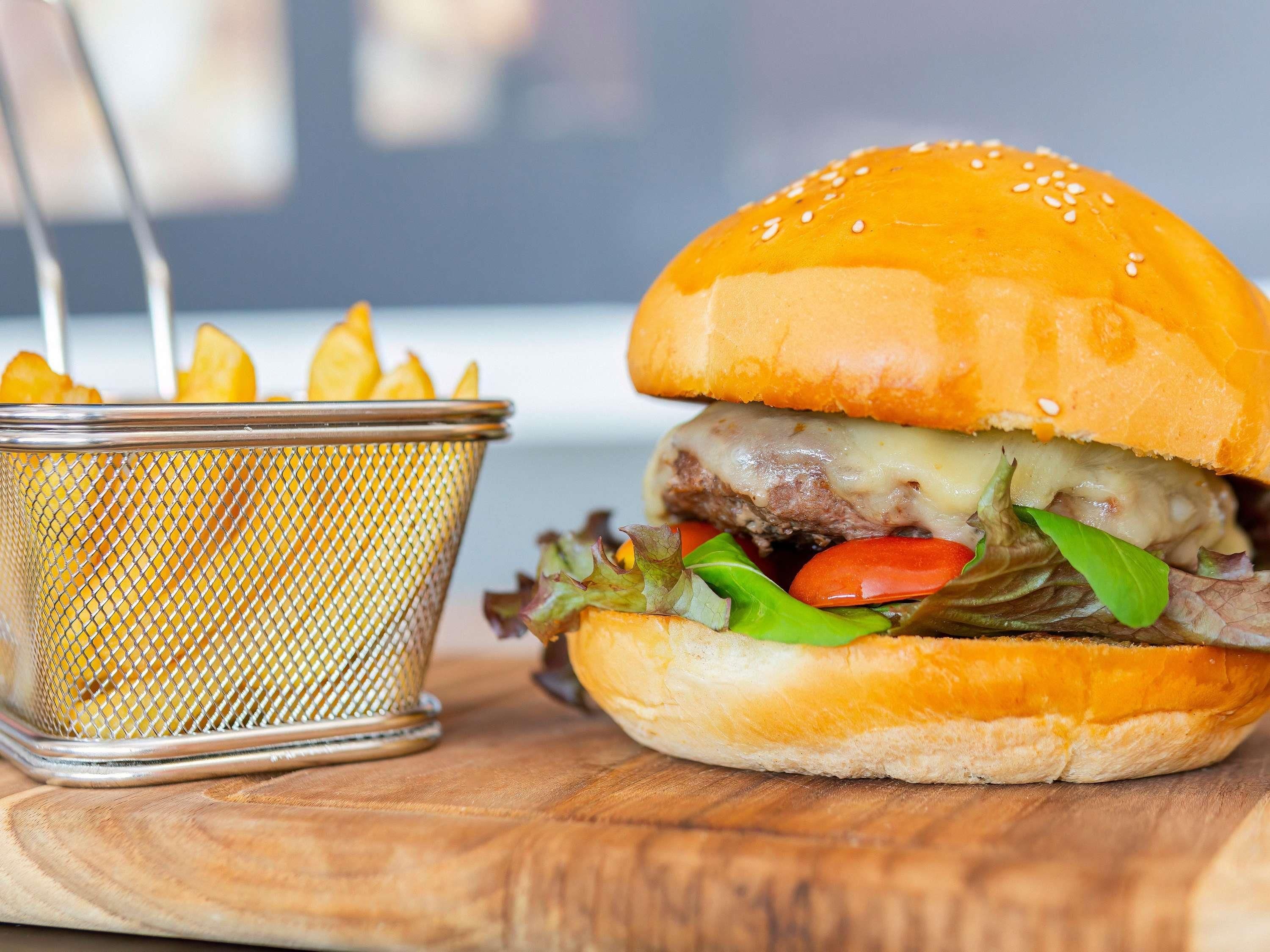 Un hamburger avec de la laitue, des tomates et du fromage, accompagné d’une portion de frites.