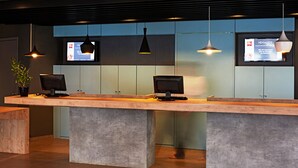 A reception desk with two computer monitors, a potted plant, and pendant lighting. - ibis Londrina Shopping (Londrina)