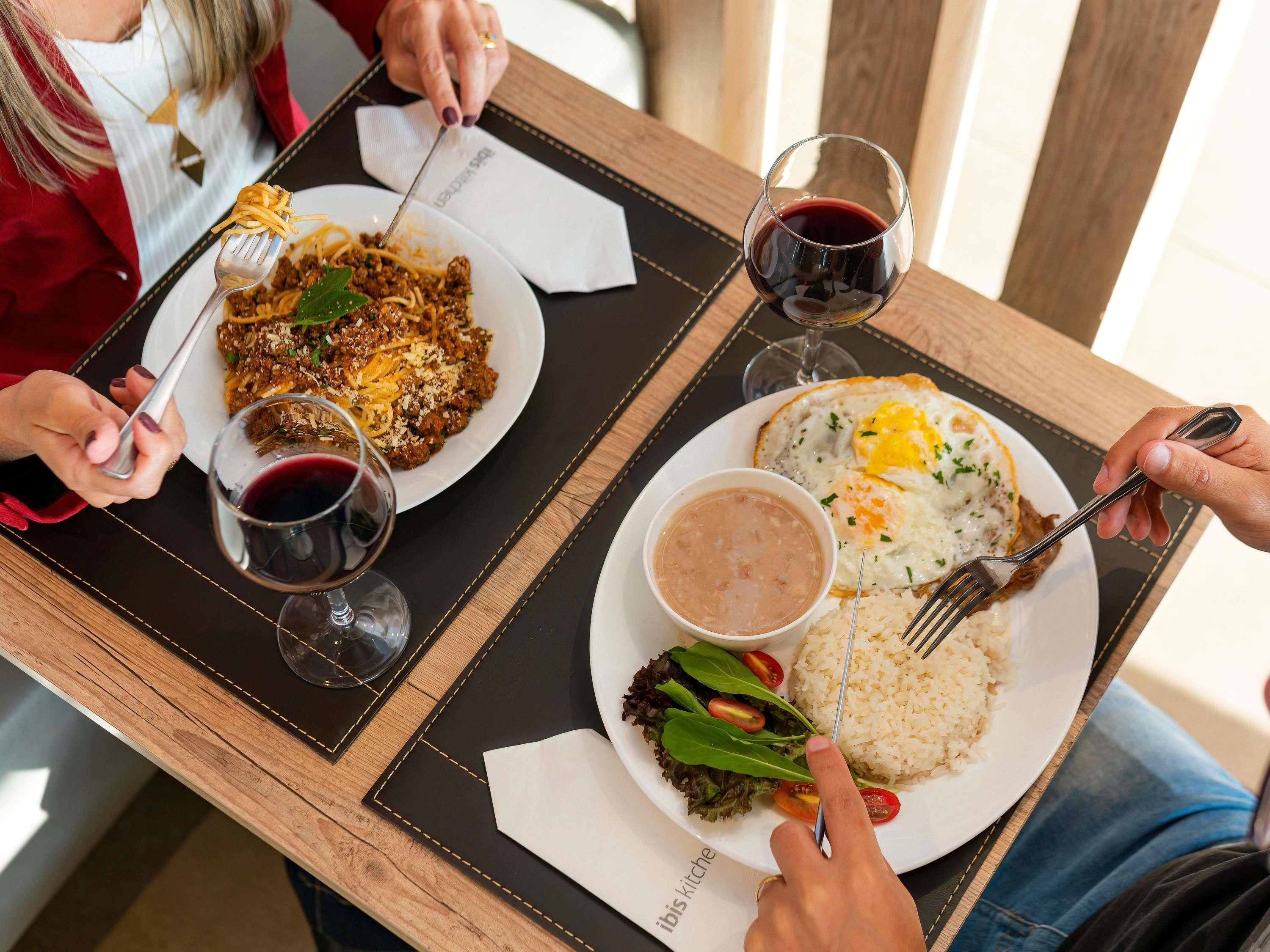 A dining table with plates of food, wine glasses, and cutlery.