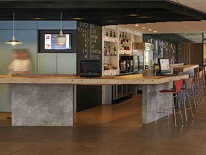 A modern bar area with a long counter, stools, and a menu board. - ibis Londrina Shopping (Londrina)