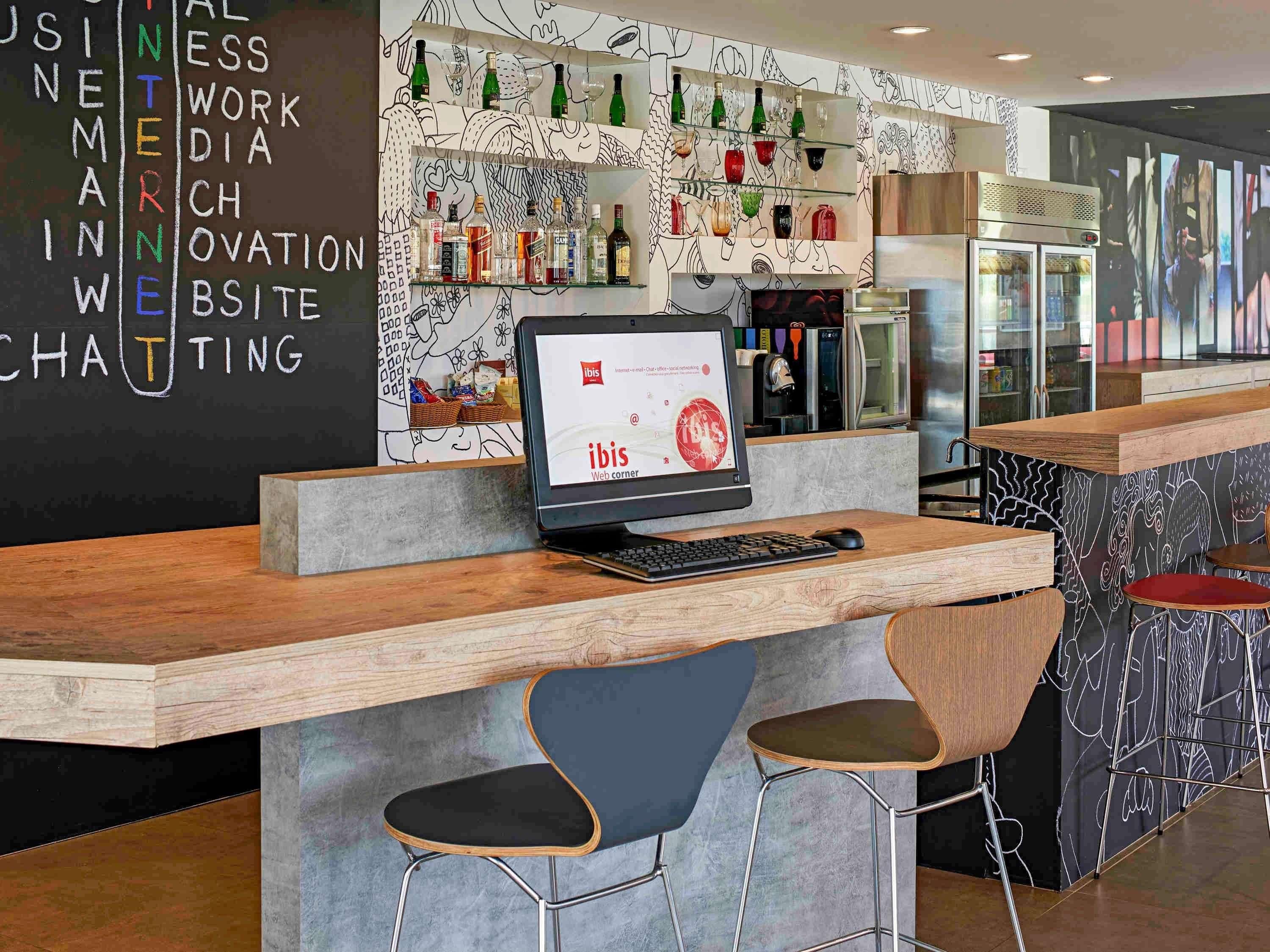 A modern bar area with a computer monitor, keyboard, and two bar stools.