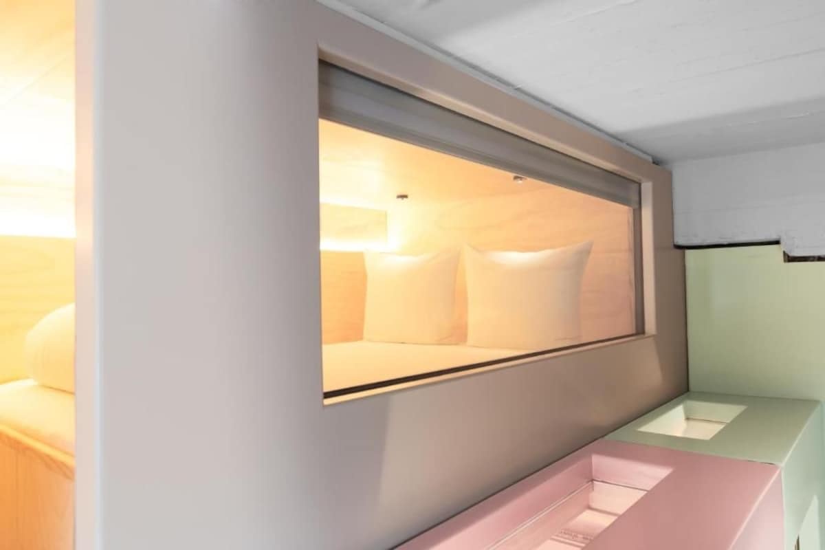 Une chambre moderne avec un lit, une fenêtre et un banc rose.