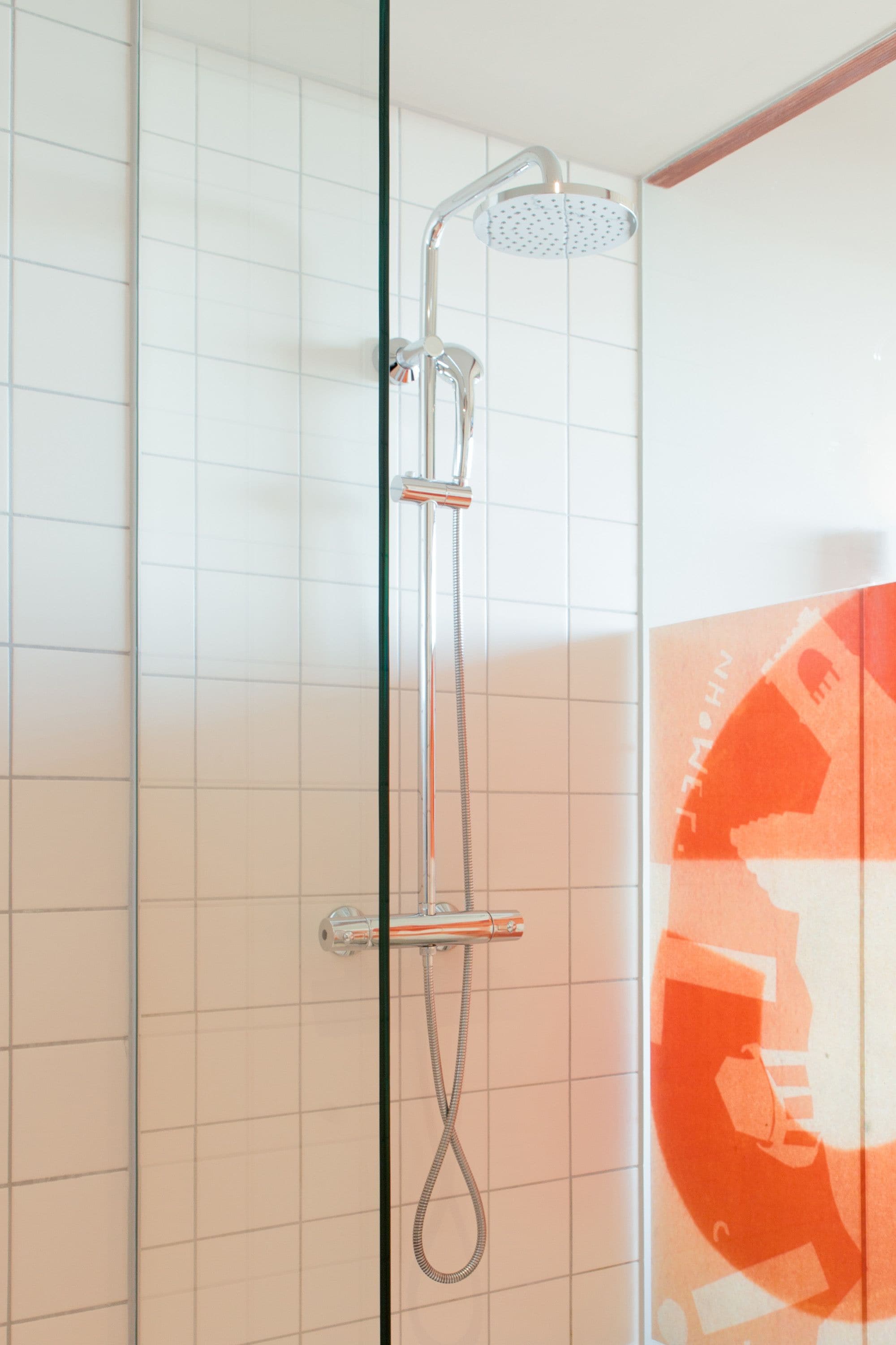 Une douche équipée d’un pommeau de douche à main et d’un panneau de commande fixé au mur.