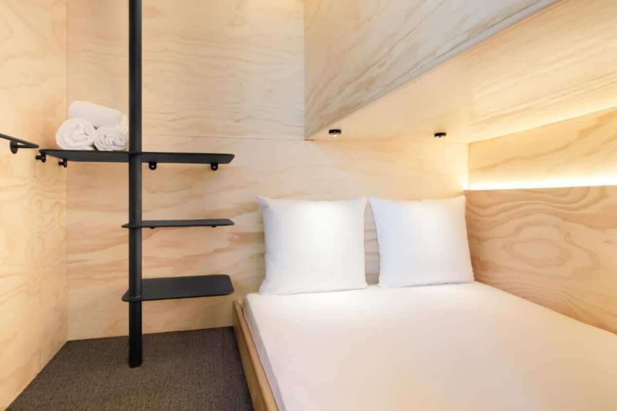 Una habitación compacta con una litera, un estante con toallas y una mesita de noche pequeña.