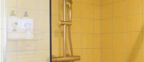 A shower with a handheld showerhead and a wall-mounted faucet.