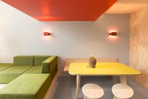 Une pièce moderne avec un canapé vert, une table jaune et un cactus posé sur la table.