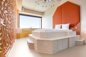 A modern bedroom with a unique geometric headboard, a large window, and a decorative wall.