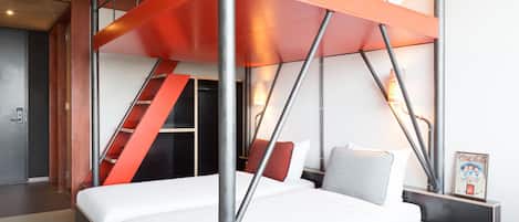 A modern hotel room with a bunk bed, a staircase, a nightstand, and a framed picture.
