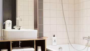 Een moderne badkamer met een grote spiegel, een witte wastafel, een douche en een bad.