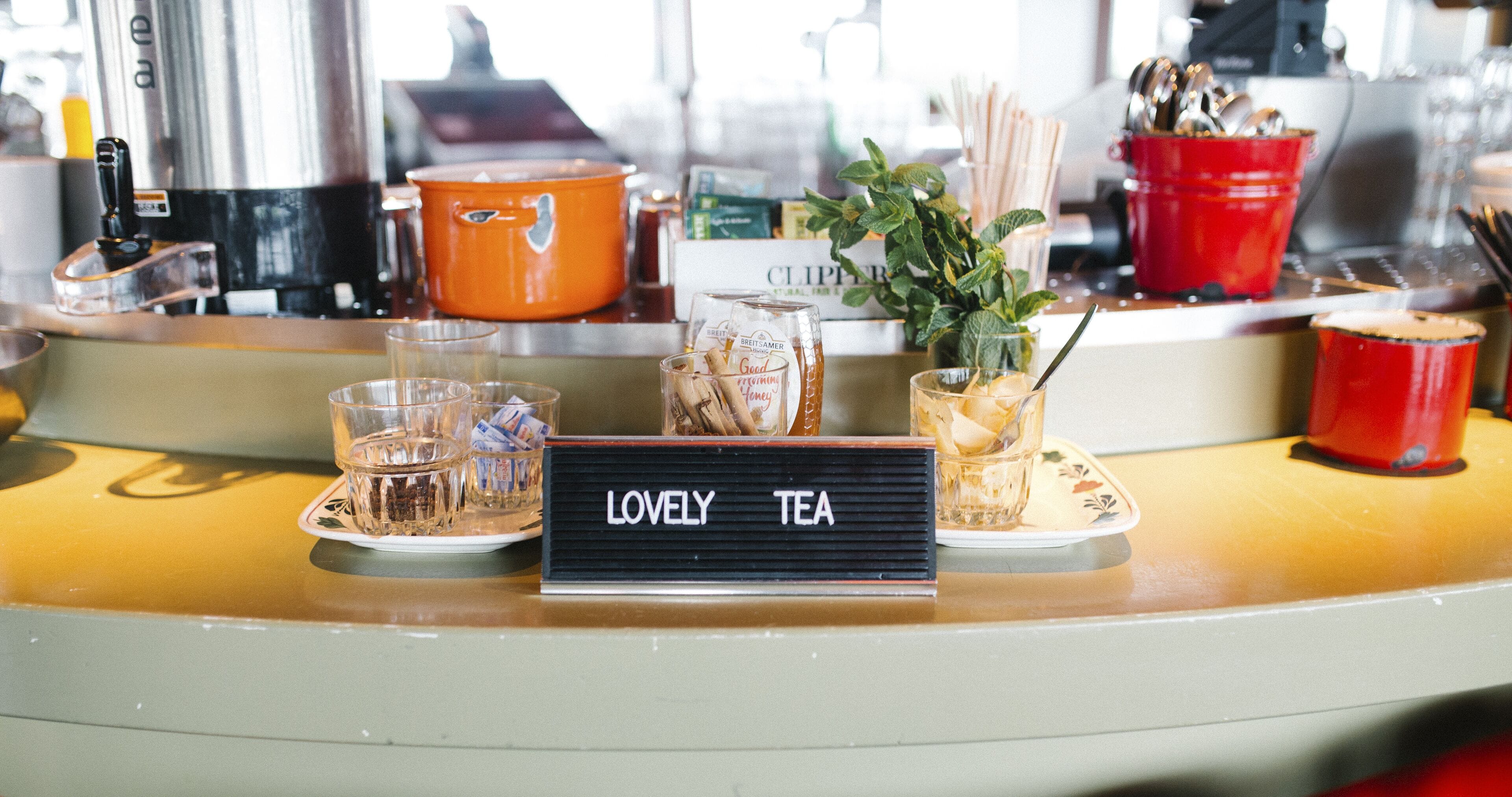 Una barra con un letrero que dice "LOVELY TEA" y varios artículos relacionados con el té.