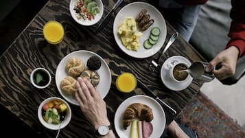 Una mesa de desayuno con diversos platos, incluyendo croissants, huevos y fruta.