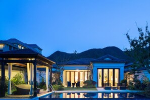 Ein modernes Haus mit Schwimmbad, großen Fenstern und einer Bergkulisse.