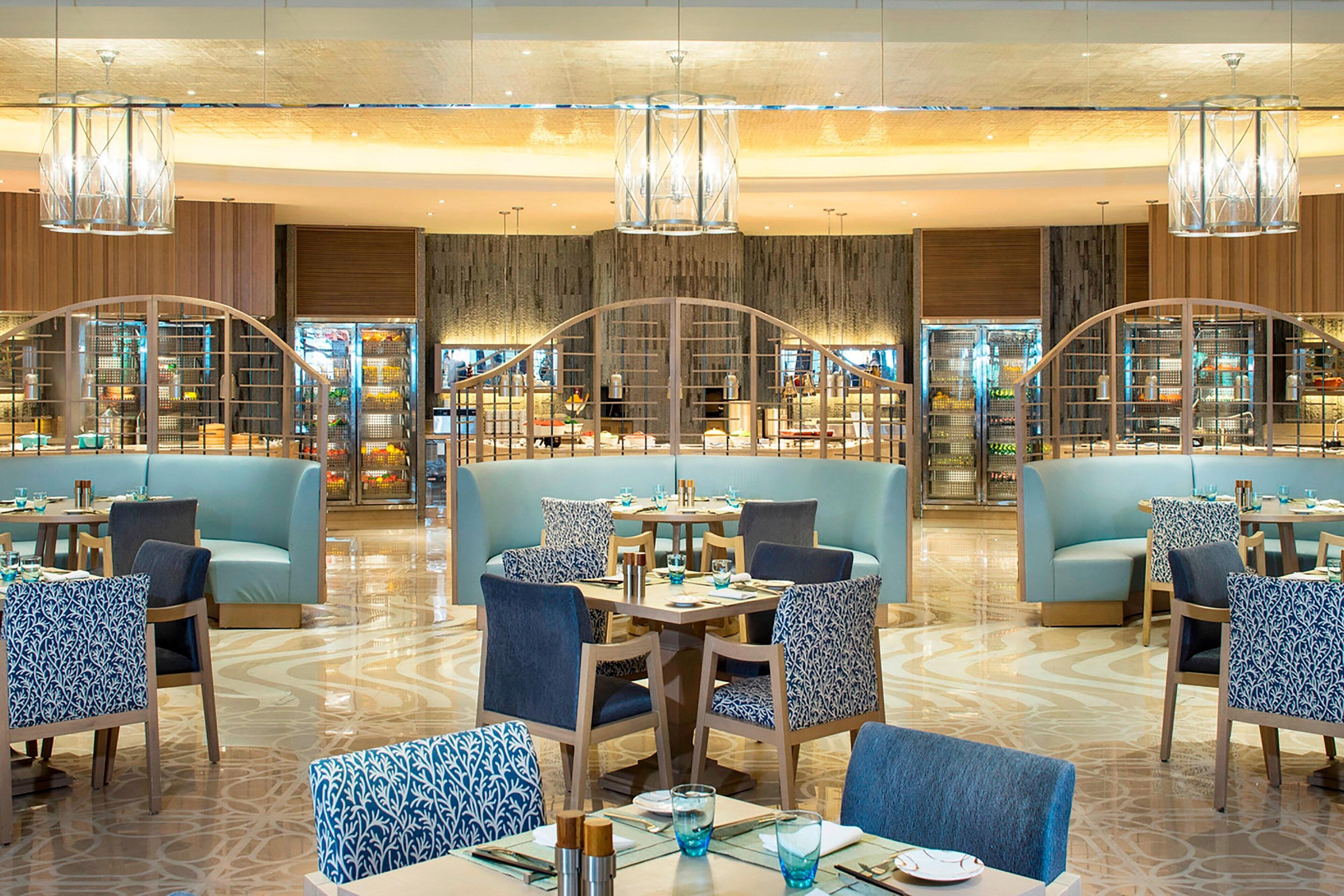 Un restaurante moderno con mesas altas, asientos tapizados en azul y sillas con estampado.