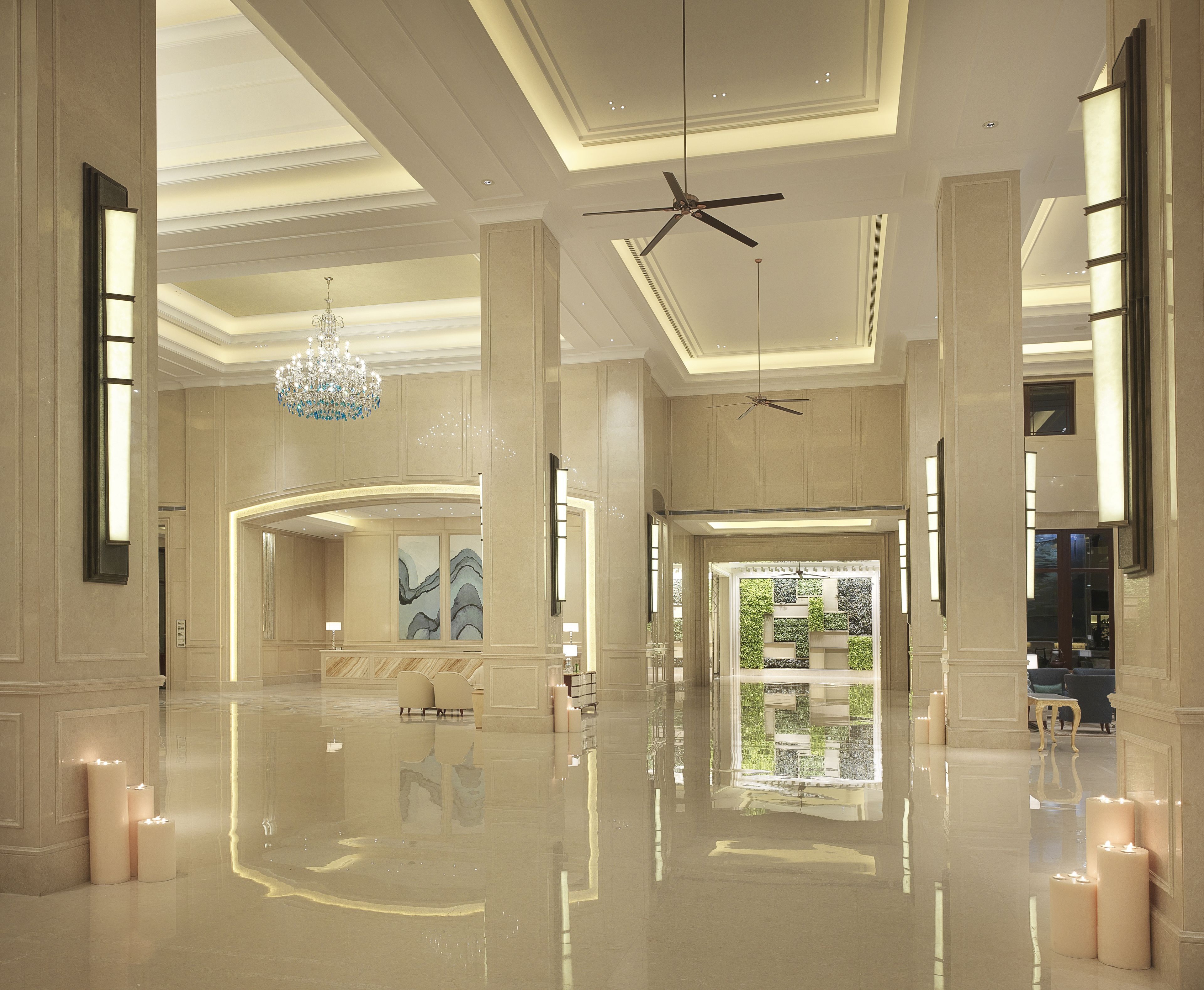 A spacious lobby with a high ceiling, chandeliers, and a large window offering a view of greenery.