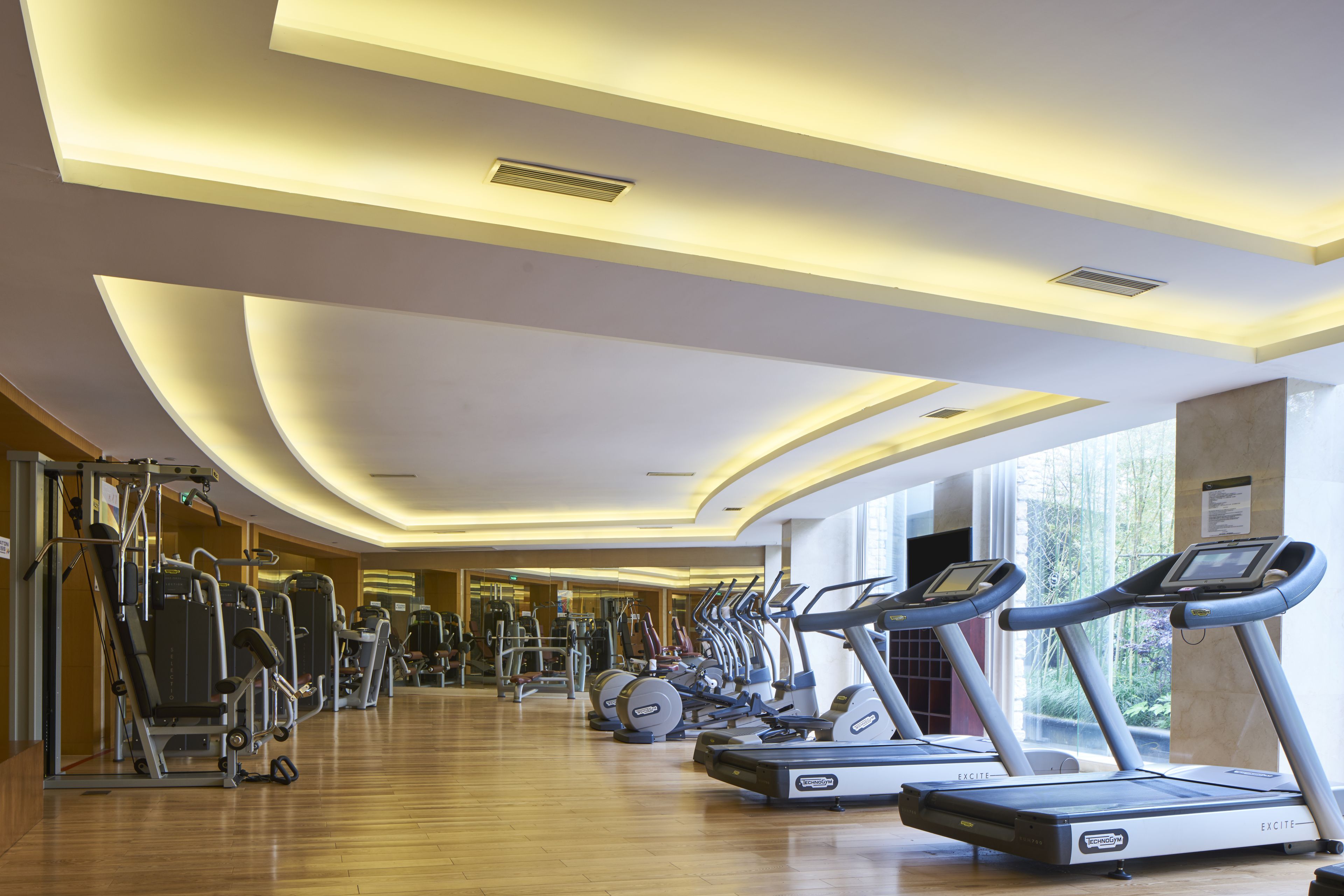 Une salle de sport équipée de tapis de course, de vélos elliptiques et d'appareils de musculation.