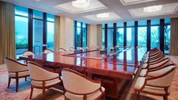 A conference room with a long table and chairs, large windows, and chandeliers.