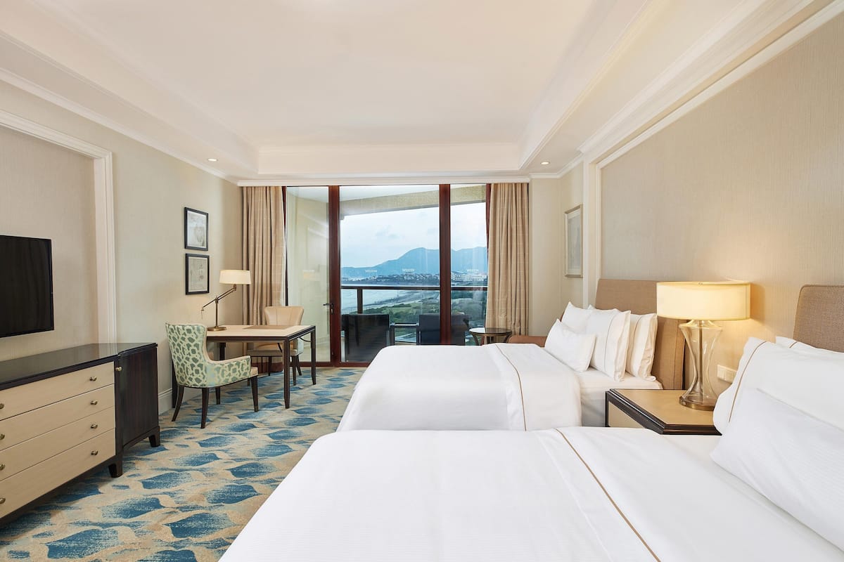 Une chambre d’hôtel avec deux lits, un bureau, une chaise et un téléviseur.