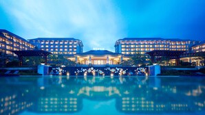 A hotel with a large reflective pool in front, multiple buildings with illuminated windows, and a clear sky. - The Westin Zhujiajian Resort, Zhoushan (Zhoushan)