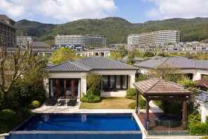 A hotel with a swimming pool, a covered patio, and a view of surrounding buildings and hills. - The Westin Zhujiajian Resort, Zhoushan (Zhoushan)