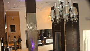 Eine Lobby mit einem modernen Kronleuchter, einem Empfangstresen und einer Treppe.