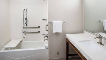 A modern bathroom with a white bathtub, a vanity with a mirror, and a towel rack.