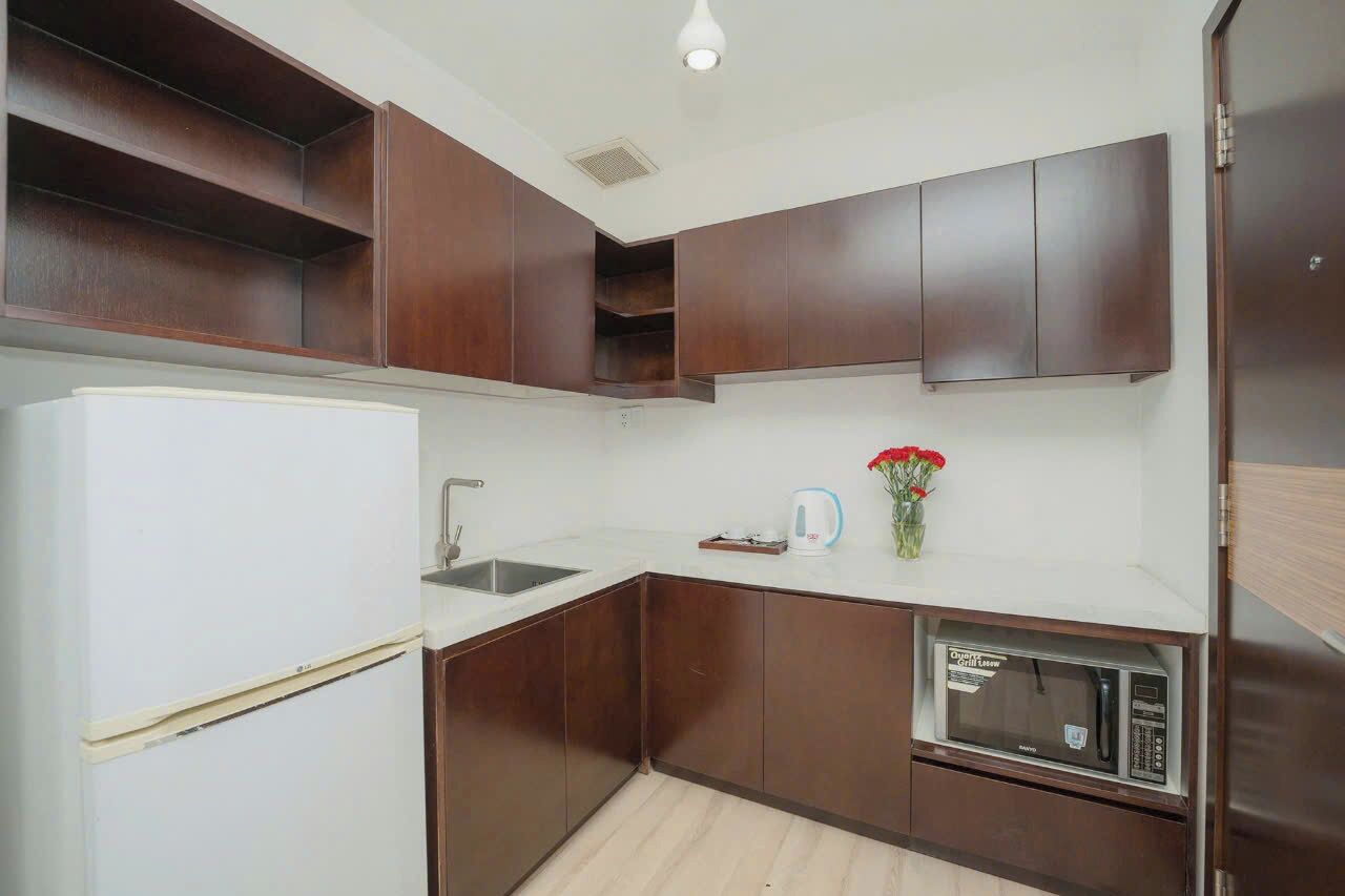 A kitchen with dark brown cabinets, a white refrigerator, a microwave, and a sink.