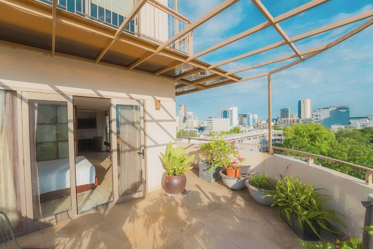 Un balcón con vista a la ciudad, plantas en macetas y una cama.