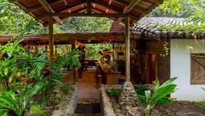 A rustic wooden structure with a stone pathway leading to a covered seating area. - Rancho Margot (Tronadora)