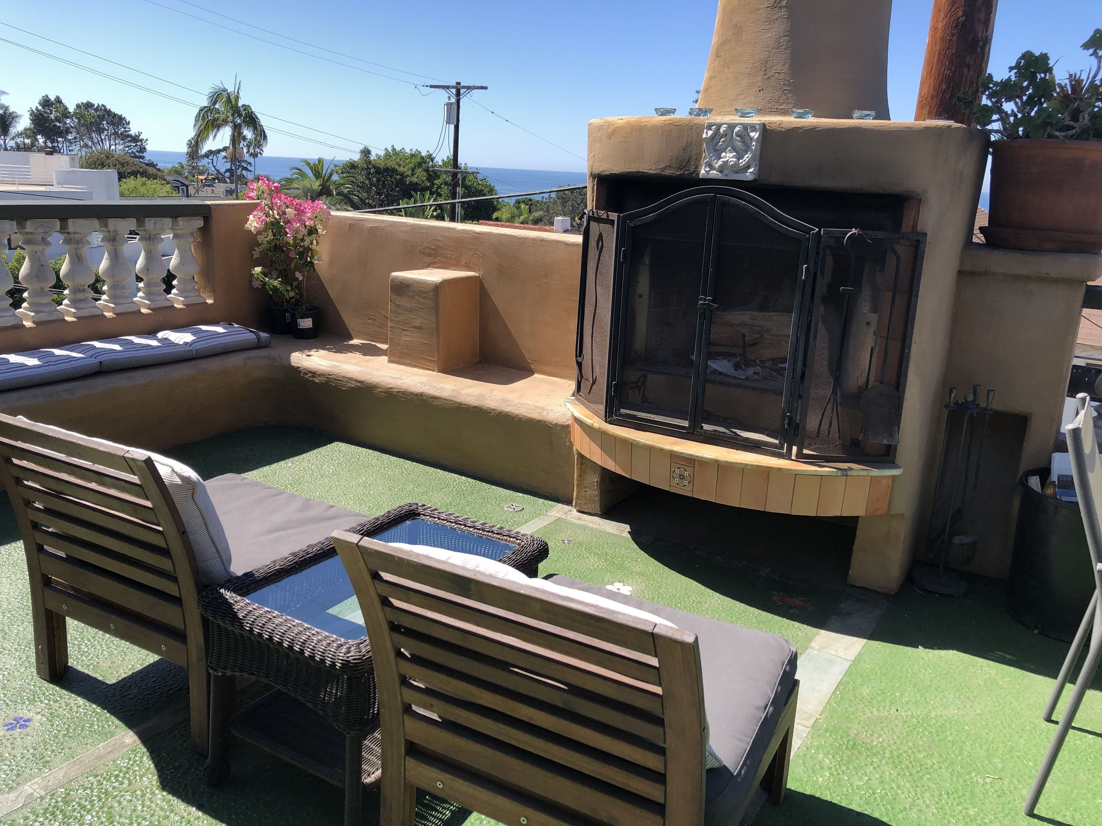 A patio with outdoor furniture, a stone fireplace, and a view of the ocean.