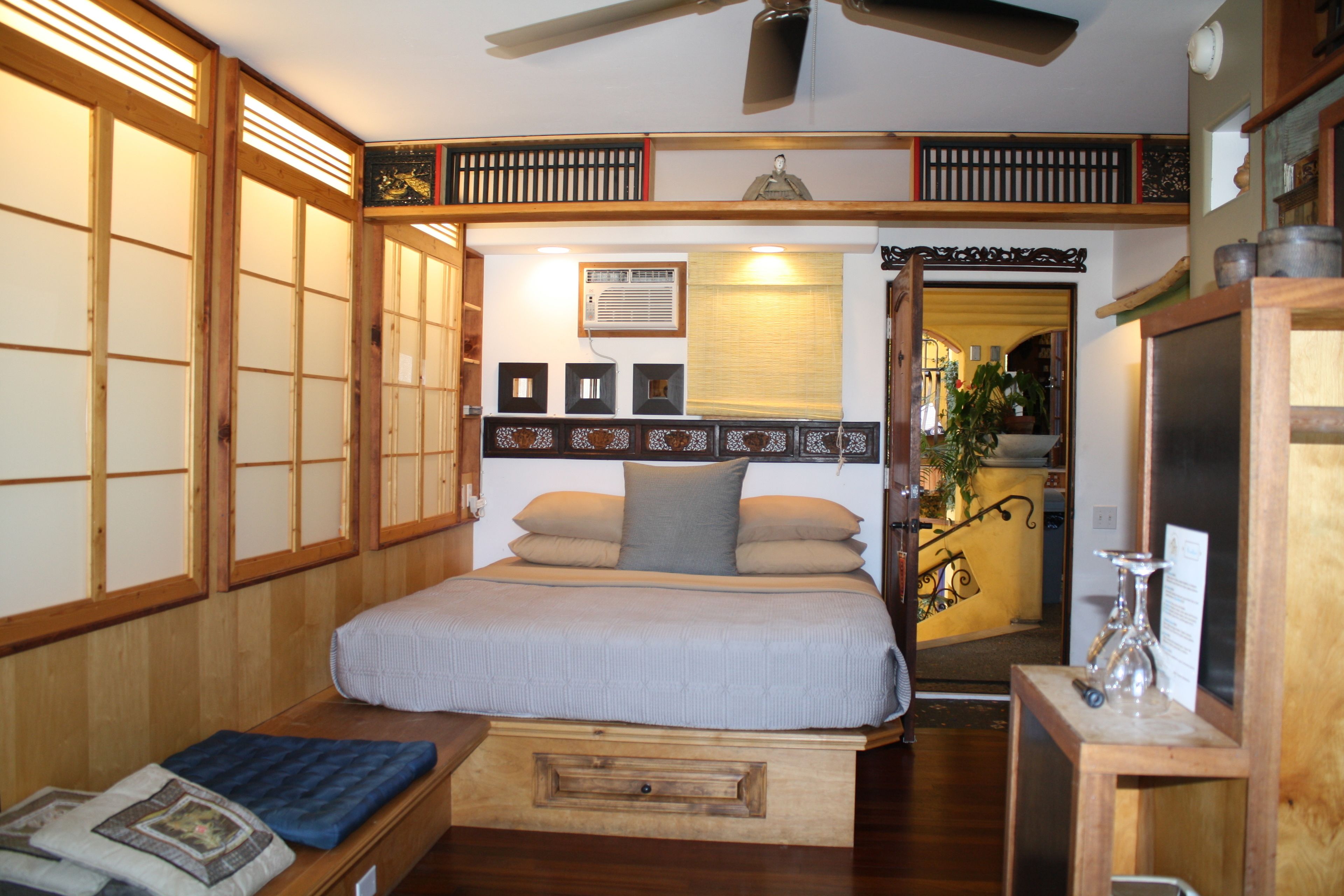 A traditional Japanese-style bedroom with a bed, wooden sliding doors, and a ceiling fan.