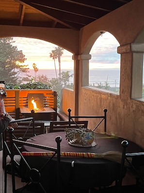 Eine Terrass mit Feuerstelle, Sitzgelegenheiten und Meerblick.