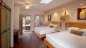 A hotel room with two beds, a ceiling fan, a skylight, a statue, and a painting. - Les Artistes Inn (Del Mar)