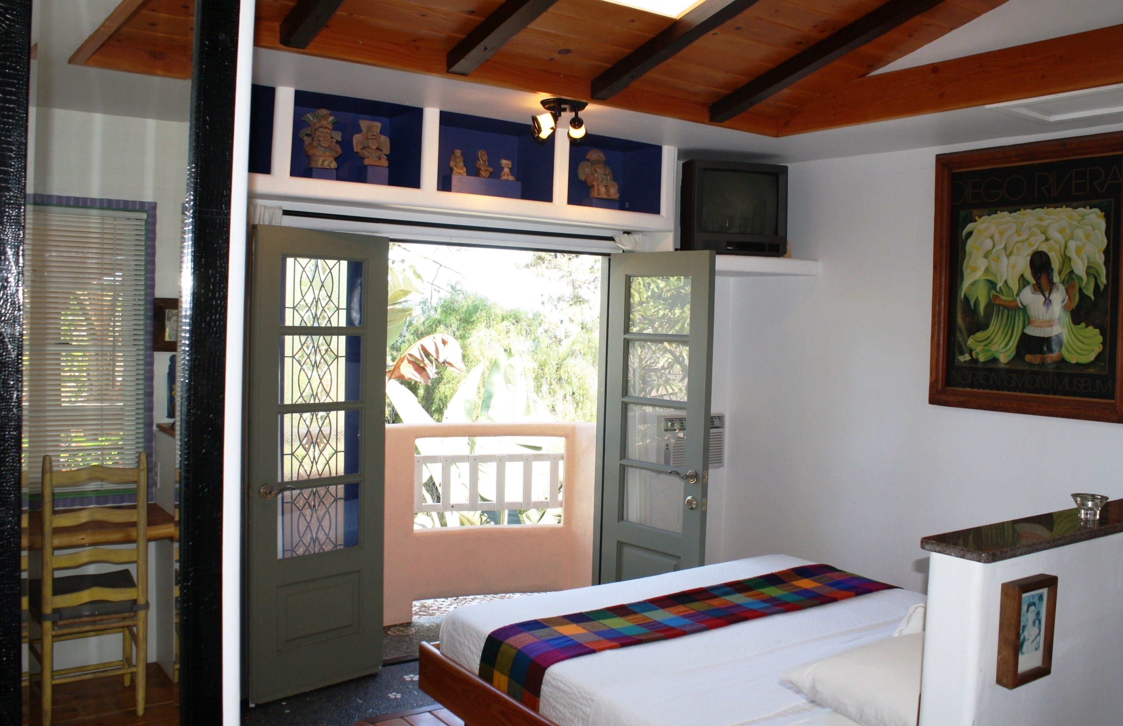 Un dormitorio con una cama, una ventana con vistas y una puerta que da a un espacio exterior.