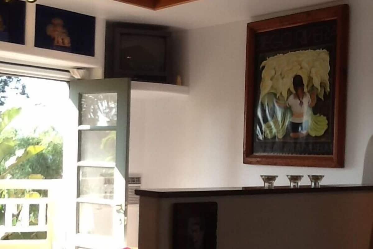 A room with a large window, a painting, and a small table with two cups.