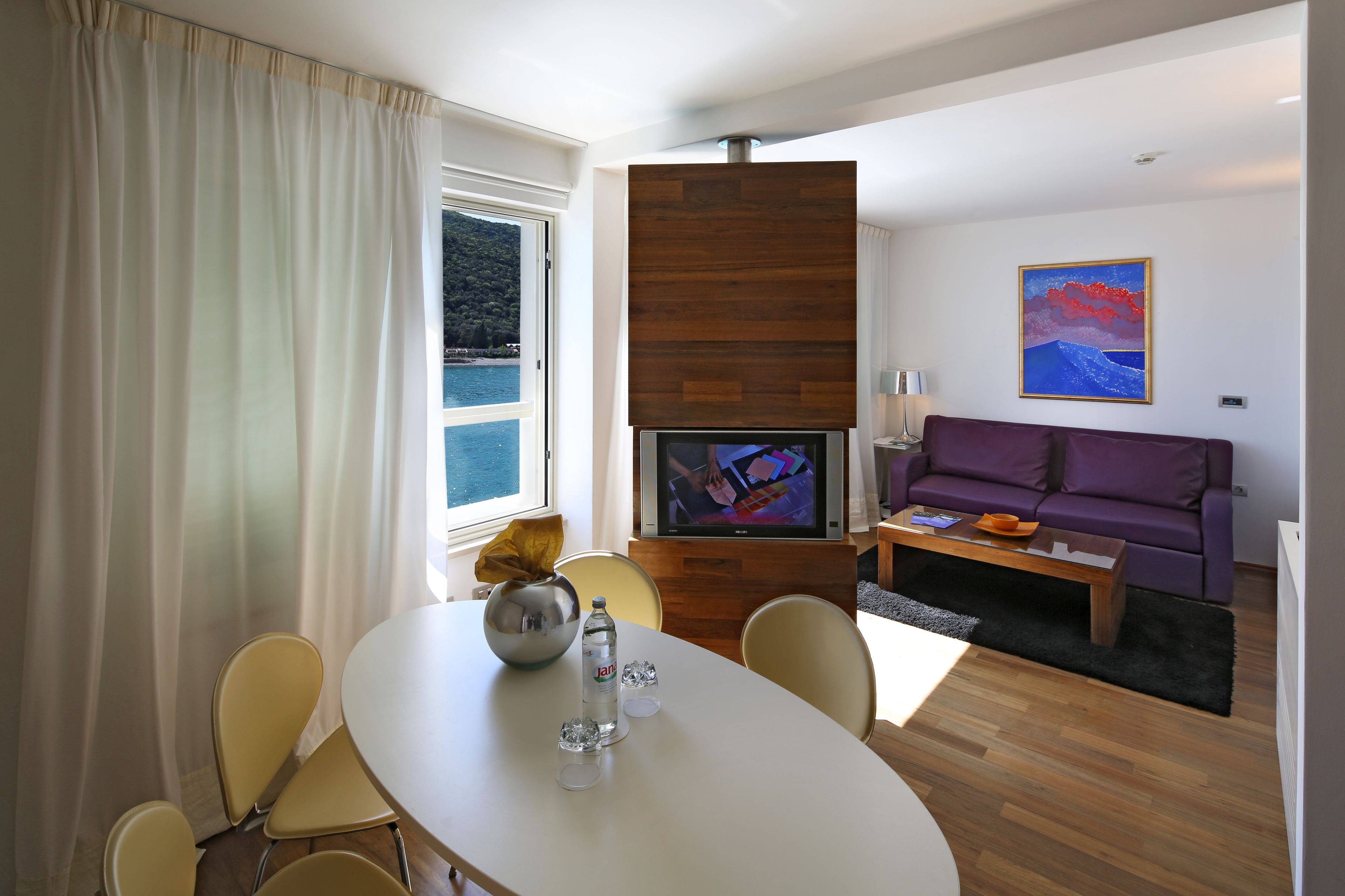 Una sala de estar moderna con comedor, televisor y sofá púrpura.