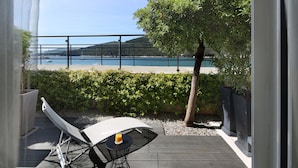 Een terras met een loungeruimte en tafel, met uitzicht op een waterpartij en heuvels.