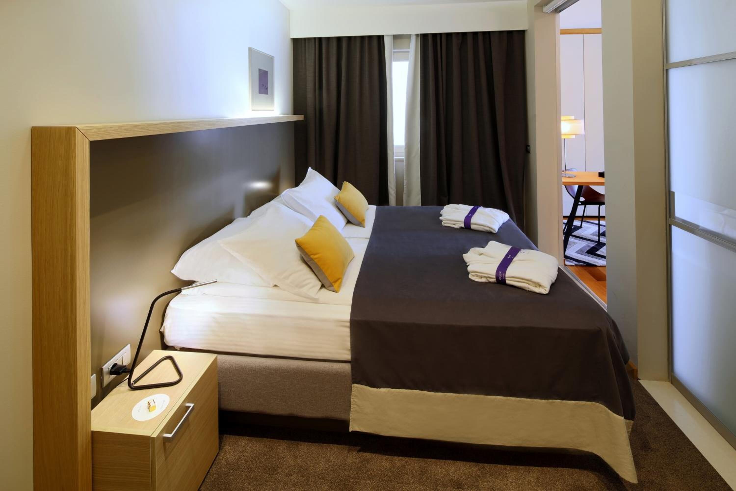 Una habitación de hotel con dos camas, una mesita de noche, un escritorio y una silla.
