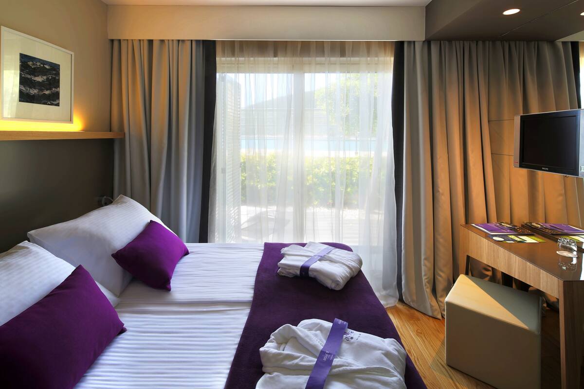 A hotel room with two beds, a TV, and a desk with a computer.