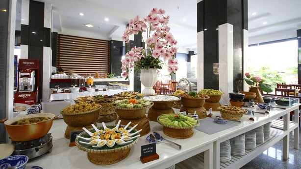 A buffet with various food items and a decorative orchid centerpiece. - SOCO Hotel (Da Nang)
